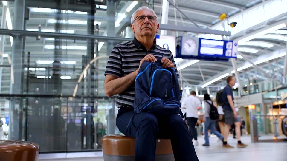 Man sits with backpack on lap at public transportation station