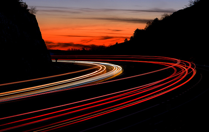 Bright curved lines through sharp turn in road between two mountains