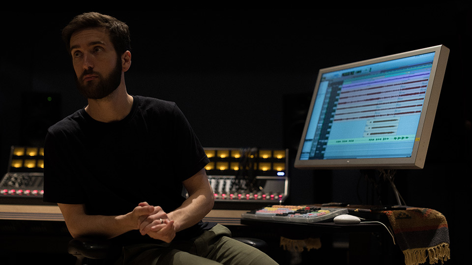 Man at computer with mixing equipment.