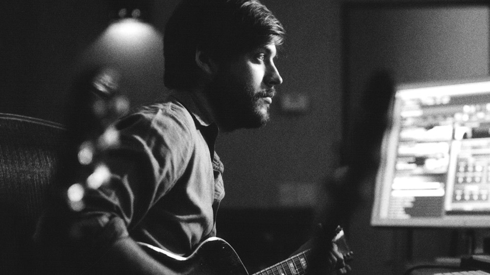 Man at computer with guitar.